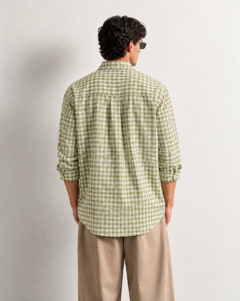 man in green gingham shirt against cream wall